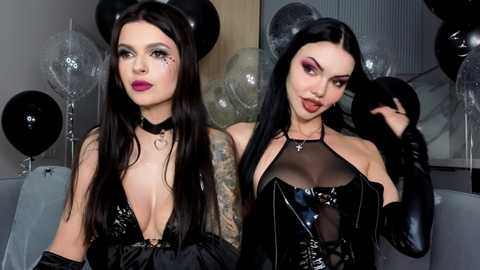 Video of two women with pale skin, black hair, and tattoos, wearing black latex dresses with cutouts, posing against a dark background.
