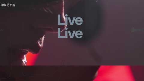 A video of a dimly lit room with a person in a black suit, holding a rope, against a dark background. The text \"Live Live\" is overlaid in white.