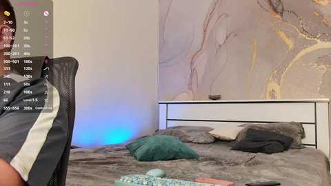 Video of a modern bedroom with a gray bed, textured wallpaper, and a black office chair. The room is softly lit with blue and white hues, creating a cozy atmosphere.