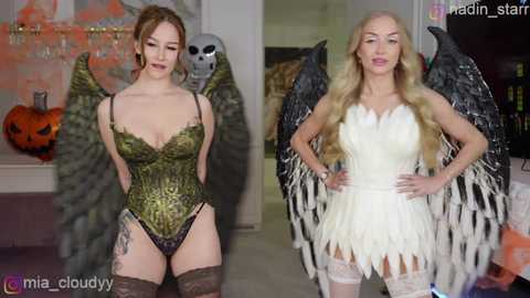 Video of two women in Halloween costumes: a green, lace bodysuit with wings, and a white, feathered, angelic dress. Both have light skin and long hair.