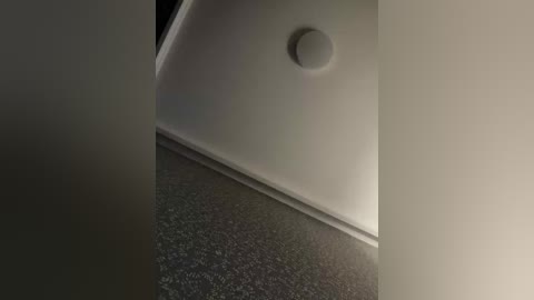 A video of a modern, sleek, white sink with a circular drain, set against a dark, textured countertop. The lighting is soft, creating subtle shadows, and the background is blurred. The image emphasizes minimalist, clean lines and contemporary design.