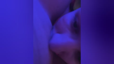 A blurred, close-up video of a nude person with light skin, under purple lighting, with a focus on the chest area, suggesting a sexual context.