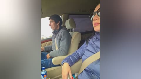 A video of a man and woman in a car, wearing casual attire, with a glass bottle on the seat, taken from inside the car.