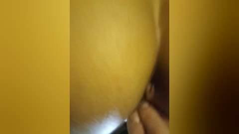 A close-up video of a hand holding a yellow fruit, possibly a banana or a lemon, with the background blurred. The image is highly pixelated and out of focus.