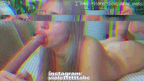 A blurred, colorful live-streaming video shows a blonde woman in a bikini sucking a large, veiny penis, with the text \"I'll live there soon, clear ones\" overlaid.