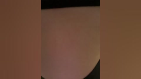 Video of a close-up, blurred view of a person's torso, with a focus on the left side of the chest, revealing a small mole and a hint of a bra strap.