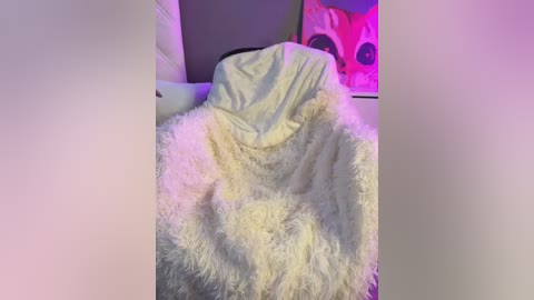 Video of a white fluffy blanket covering a bed, with a pink pillow and a vibrant, abstract art piece in the background.