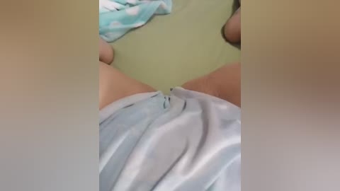 Video of a person's lower torso, wearing light blue and white polka-dot underwear, with light skin. Background includes a green wall and a partially visible blue towel.