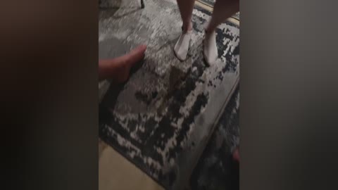 Video of a close-up scene featuring a hand and bare feet on a gritty, gray, textured surface, likely concrete or stone, with shadows indicating movement.