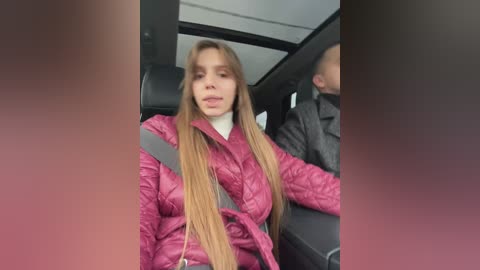Video of a young woman with long blonde hair, wearing a pink quilted jacket, sitting in the backseat of a car with a gray-haired man in the driver's seat.