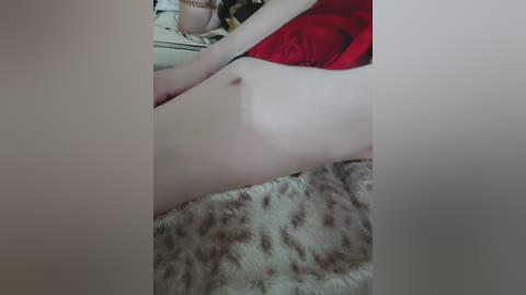 A video shows a partially nude woman with fair skin, lying on a bed with a patterned blanket. Her breasts are visible, and she is wearing a red top.