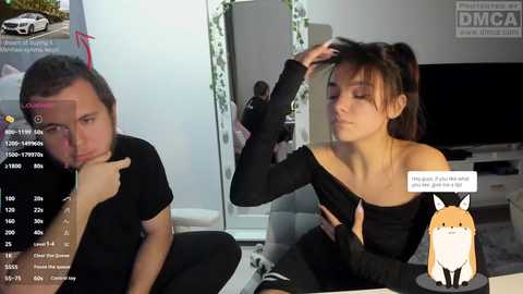 A video of two women in a modern living room, one fixing the other's hair. The room features a large mirror, a white couch, and a TV.