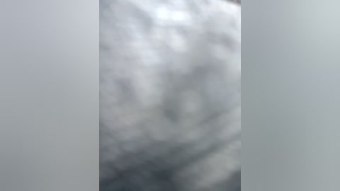 A blurred video of a cloudy sky with soft, grayish-white hues. The image features indistinct shapes and textures, suggesting a lack of clarity or focus. The background is predominantly gray with subtle variations in tone.
