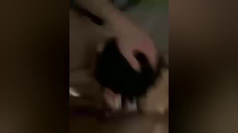 Video of a dimly lit room showing a person, possibly male, in black clothes, bending over, with hands on their knees. Background is blurred and dark.