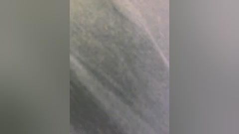 A video of a dark, marbled granite countertop with a textured, veined pattern in shades of gray and white, set against a neutral gray backdrop.