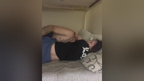 A video shows a tattooed man, shirtless, hugging a woman with short dark hair, both lying on a bed with patterned sheets. The room is dimly lit.