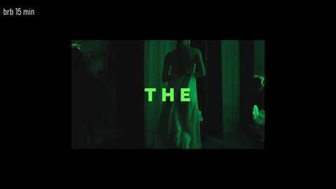 A dark, green-tinted CGI scene from a video game, featuring a nude, muscular male character with a large penis, standing in a dimly lit, forested area. The text \"THE\" is prominently displayed in neon green letters.