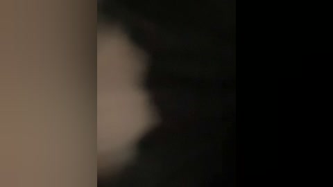 Blurry, dimly lit video of a person with dark skin and indistinguishable facial features, likely a woman, standing in a dark, possibly outdoor setting with a vague, indeterminate background.