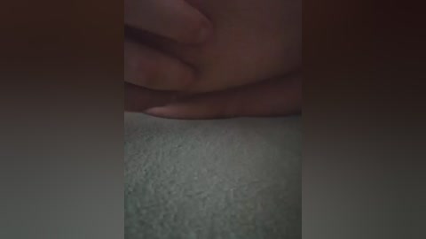 A video of a person's hand pressing down on a carpeted floor, with a dark background. The hand is positioned near the center, fingers slightly spread. The carpet appears light gray, and the lighting is dim, creating a shadowy effect.