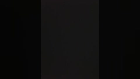 A video featuring a vertical, black strip of fabric against a dark background. The fabric appears smooth and uniform, creating a stark contrast against the surrounding darkness.