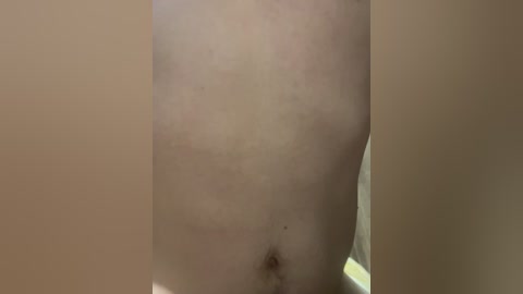 Video of a close-up, bare, pale skin abdomen with a small, dark mole, and light-colored, soft background. The image focuses on the midsection, excluding facial or upper body features.