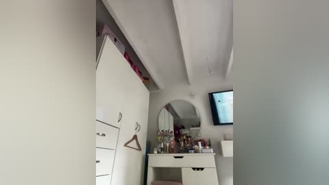 Video of a minimalist, white, clutter-free room with a vanity mirror, shelf, and small TV. The room has clean lines and a simple, modern aesthetic.