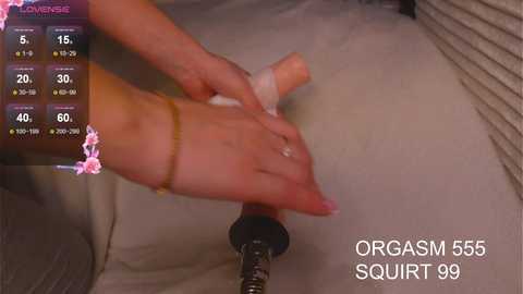 Video of a woman's hand with a pink ring and a bracelet, applying a condom to a vibrating sex toy, labeled \"Orgasm 855 SQUIRT 99.\