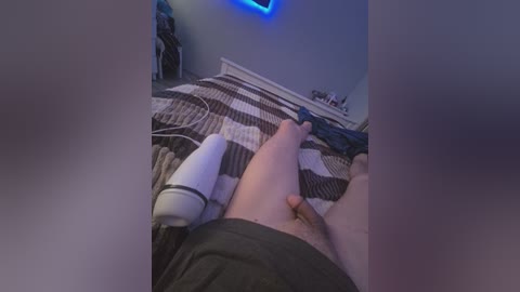 Video of a person lying on a bed with a white robotic arm on their lap and a black blanket.