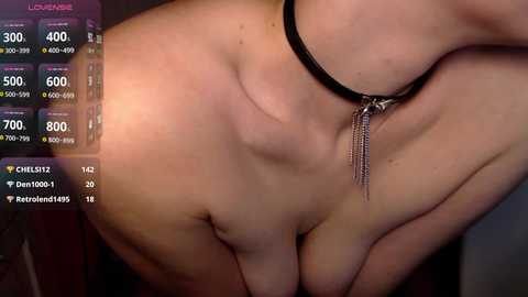 Video of a nude woman with light skin, wearing a black choker with tassels, lying on her side, displaying her breasts and torso. The background is blurred, with a digital interface displaying live stream details.