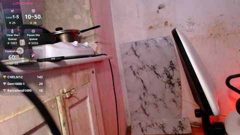 Video of a cluttered, poorly lit kitchen with a white stove, a black pan, and a cracked marble countertop. The background is a white wall with noticeable dirt and stains.