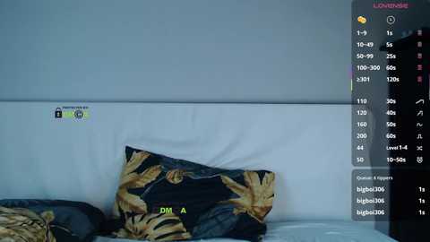 A video shows a bed with a white headboard, featuring a pillow with a black and gold tiger print design. The background is a plain white wall. A digital screen displays a live streaming platform with text and video options.