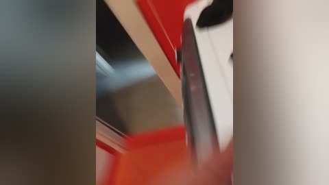 A close-up video of a shiny red and white car, showcasing its metallic paint and chrome accents. The background is blurred, emphasizing the car's sleek design and reflecting light.