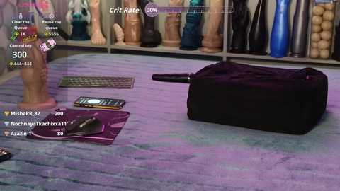 A video showing a virtual reality game where a large, black, cylindrical object is lying on a purple, textured floor. Surrounding the object are various sex toys and a smartphone.