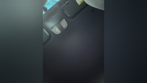 A dimly lit video of a black, textured surface with a rectangular, silver button and a blue light on the upper left. The background is blurred and dark, creating a moody, mysterious atmosphere.