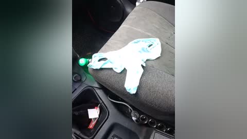 A video shows a pair of white and blue patterned panties discarded on a gray car seat, with a green power outlet nearby.