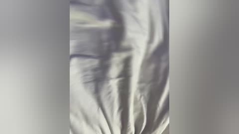 A close-up video of a wrinkled, white bedsheet with soft, crumpled texture, displaying subtle folds and creases. The background is blurred, focusing solely on the fabric's intricate details.