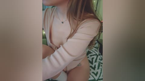 Video of a light-skinned woman with long brown hair, wearing a sheer pink top revealing her breasts and a floral-patterned skirt.