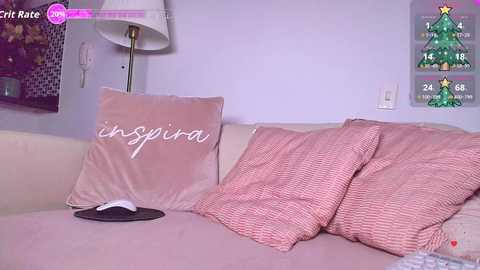 A video of a cozy living room with a beige couch, pink striped pillows, a white lampshade, and a festive calendar featuring a Christmas tree.