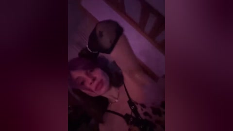 A blurry video shows a young woman with fair skin and shoulder-length brown hair, wearing a black bra, lying on a wooden floor. The background is dimly lit with purple hues, creating a moody atmosphere.