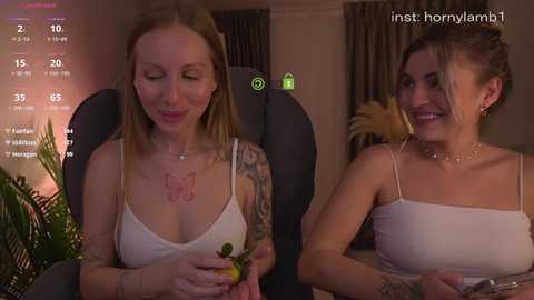 Video of two women in casual attire, one with a tattoo sleeve, the other with a tank top, seated on a black chair, indoors, dim lighting, and a digital overlay showing social media statistics.