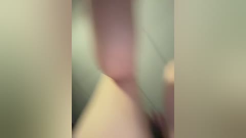 A blurry, abstract image featuring soft, pastel hues and indistinct shapes, likely representing a human figure. The image lacks clear details and sharpness, making it difficult to discern specific features or context.