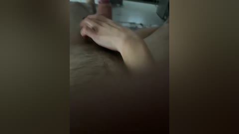 A dimly lit video shows a close-up of a hand grasping a penis, likely in a bathroom setting with a blurred background.