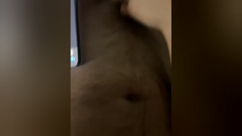 A blurry, dimly-lit video shows a person's upper torso with a hint of light skin tone and indistinct features. The background is dark, with indistinct objects.