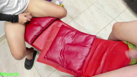 A video showing a woman's legs on a red leather bench, wearing a grey shirt and black shoes.