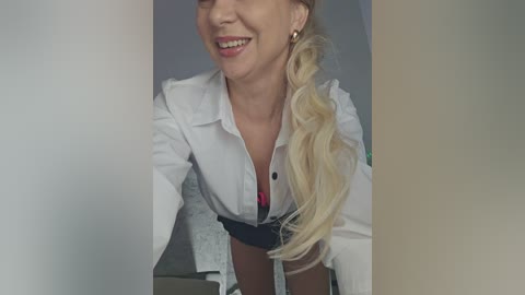 Video of a smiling, blonde woman in a white lab coat, revealing a red bra underneath.
