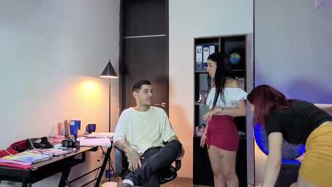 Video of a modern, minimalist bedroom with a young man and woman, both with medium builds and fair skin, seated on a bed.
