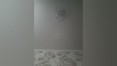 A dimly lit, misty bathroom scene with a foggy mirror and a marble floor, featuring a circular, metallic showerhead mounted on the wall.
