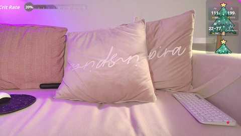 Video of a cozy living room with beige sofa, two beige pillows with \"reina\" embroidered, a keyboard on the right, and a Christmas tree in the background.