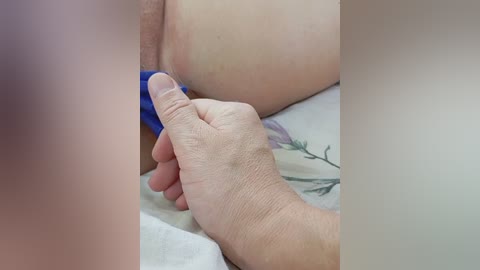 Video of a close-up scene featuring a hand pulling down blue fabric covering a person's exposed genital area, with the person's skin visible and slightly flushed.