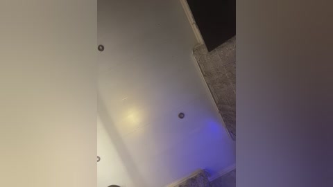 A video of a dimly lit room with a beige ceiling featuring three metal screws and a faint blue glow from an electronic device on the floor.